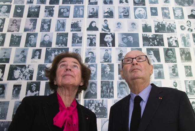 FILE - In this Tuesday, Dec. 5, 2017 file photo, French Nazi hunters Beate Klarsfeld and her husband Serge Klarsfeld look at photos of young Jews deported from France during the WWII, at the Shoah Memorial in Paris, France. French famous Nazi hunter Serge Klarsfeld was awarded France's highest honor, the Grand Cross of the Legion of Honor, in a ceremony led by French President Emmanuel Macron. (AP Photo/Michel Euler, File)