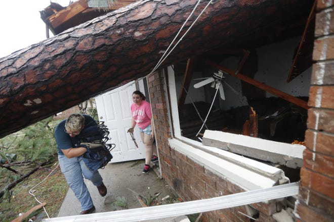 Megan Williams, left, and roommate Kaylee O'Brian take belongings from their destroyed home after several trees fell on the house during Hurricane Michael in Panama City, Fla., Wednesday, Oct. 10, 2018. (AP Photo/Gerald Herbert)