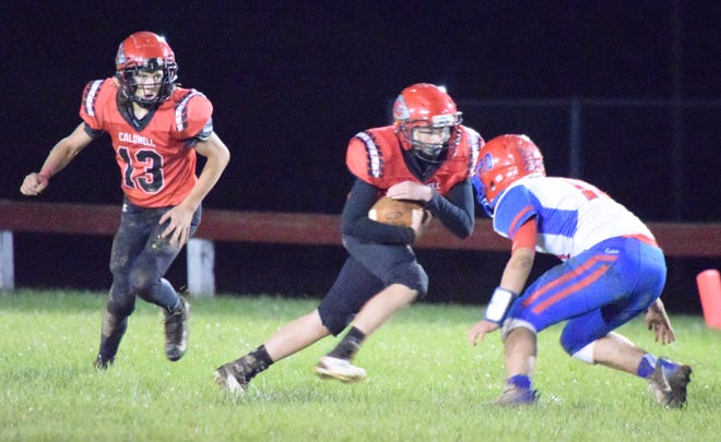 Caldwell High's Skyler VanFossen (16) protects the ball as he's about to be hit by a Fort Frye defender during Friday's PVC clash in Caldwell. Also pictured is Caden Moore (13) of the Redskins.