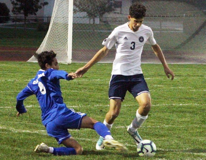 Hillsdale Academy´s Levi Socha (3) dribbles through a tackle attempt by Lenawee Christian´s Francisco Cabrera during Thursday´s ISL championship game. (JAMES GENSTERBLUM PHOTO)