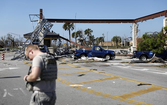 A soldier stands guard at the damaged entrance to Tyndall Air Force Base in Panama City on Thursday in the aftermath of hurricane Michael. The base sustained massive damage, and it is unclear when airmen might be able to return to the facility. [AP PHOTO/DAVID GOLDMAN]