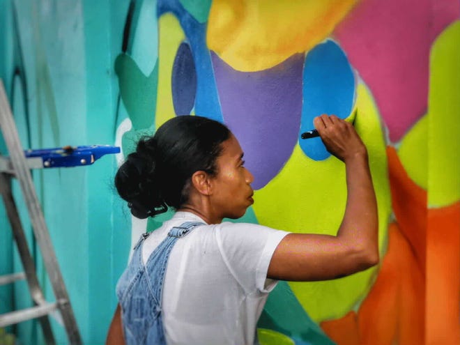 Caron Bowman, lead artist for the citywide Calypso project, painting at the Riviera Beach City Marina. [Wilkine Brutus]