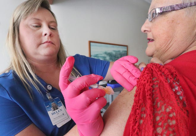 Helen Milano, a LPN at Halifax Medical Center, administers a flu shot to employee Donna Small during a recent flu shot clinic at the hospital. [David Tucker/Gatehouse Media]