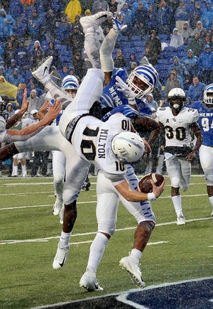 UCF's McKenzie Milton (10) dives over Memphis's Josh Perry as he scores the go-ahead touchdown on a 7-yard run during the second half Saturday in Memphis, Tennessee. [Associated Press/Mark Zaleski]