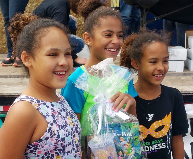 Khloe Duckett (left), 10, Ha'nya Sims, 12, and Kyla Duckett, 11, pose for a photo after the pie eating contest for ages 10 to 14 on Friday at the Haven Fall Festival. Ha'nya is holding her prizes for winning the contest. [Michael Stavola/HutchNews]