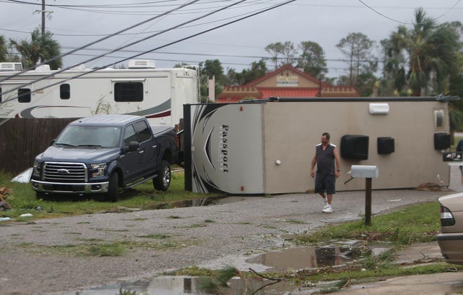 A man walks past an overturned trailer moments after the wind advisory was lifted following Hurricane Michael on Oct.10, in Panama City, Fla.