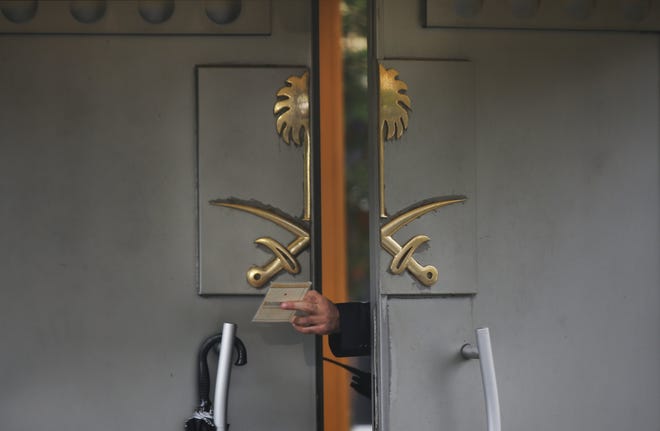 A security guard passes a document to a colleague outside Saudi Arabia's Consulate in Istanbul, on Monday, Oct. 15, 2018. [AP Photo/Petros Giannakouris]