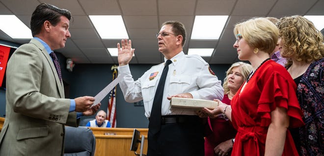 Mayor Newell Clark (left) reads the Administration of Oath as Paul Jarrett is sworn in as the new Lexington fire chief on Monday at City Hall with his wife, Nita Jarrett, daughters Kayla Smith and Sierra Jarrett and son Noah Jarrett by his side. [Dan Busey/The Dispatch]