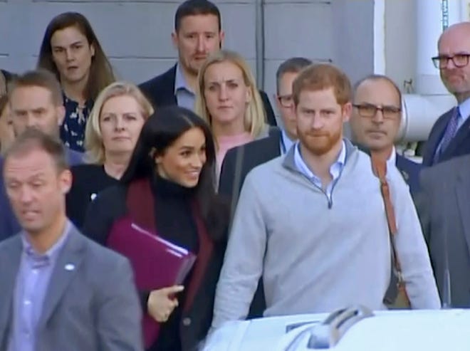 In this image made from video, Britain's Prince Harry, center right, and his wife Meghan, center left, Duke and Duchess of Sussex, approach a car at an airport in Sydney, Monday, Oct. 15, 2018. Prince Harry and his wife Meghan arrived in Sydney on Monday, a day before they officially start a 16-day tour of Australia and the South Pacific. Kensington Palace says Prince Harry and Meghan the Duchess of Sussex are expecting a child in the spring. (Australian Pool via AP)