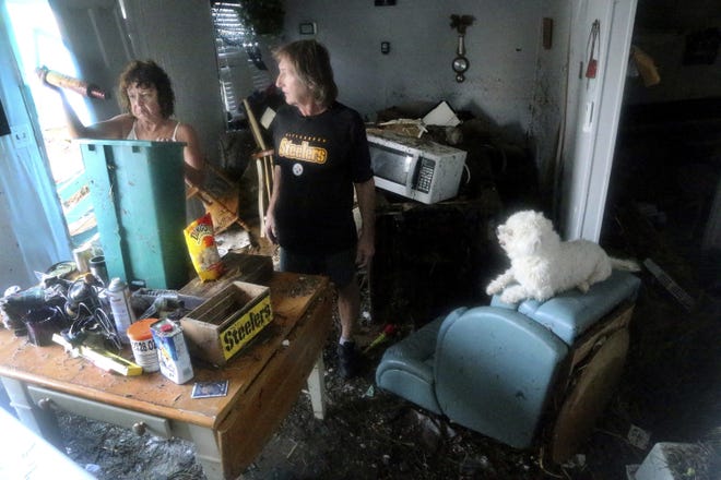 Cindy Murphy, 58, left, finds a rolling pin while searching for her husband James Murphy's medication in what remains of their home on a coastal stretch of Port St. Joe, Fla. The couple's dog, J.J., at right, survived, but they have been unable to locate their cat. Cindy was surprised to find the rolling pin, which did not belong to her and was among dozens of items from others homes which were displaced by Hurricane Michael's violent storm surge and wind as it made landfall on Wednesday in the Florida Panhandle. (Douglas R. Clifford/Tampa Bay Times via AP)