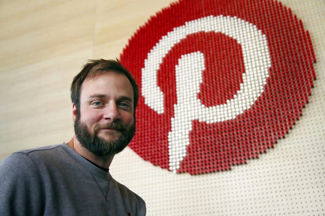 Evan Sharp, Pinterest co-founder and chief product officer, poses for a photo stands beside a wall of pegs symbolizing the company logo at Pinterest headquarters in San Francisco. "Social media is about sharing what you are doing with other people," said Sharp. "Pinterest isn't about sharing. It's mostly about yourself, your dreams, your ideas you want for your future." [AP Photo/Ben Margot]