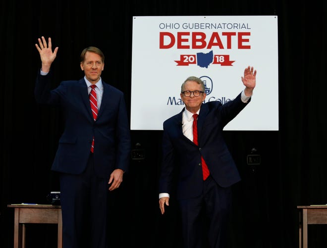 FILE - In this Monday, Oct. 1, 2018, file photo, Democratic gubernatorial candidate Richard Cordray, left, and Ohio Attorney General and Republican gubernatorial candidate Mike DeWine wave to the crowd before a debate at Marietta College in Marietta, Ohio. The two candidates are working to distinguish their positions and stave off critics from the far right and left to win Ohio's high stakes governor's race. (AP Photo/Paul Vernon, Pool, File)