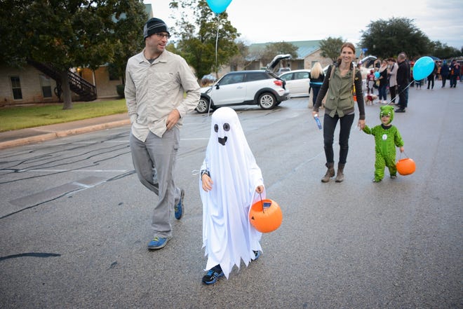 Brian and Ruth Spencer walk with their children Calvin, dressed as a ghost, and Spencer, dressed as an aligator in downtown Pflugerville. [Megumi Rooze]