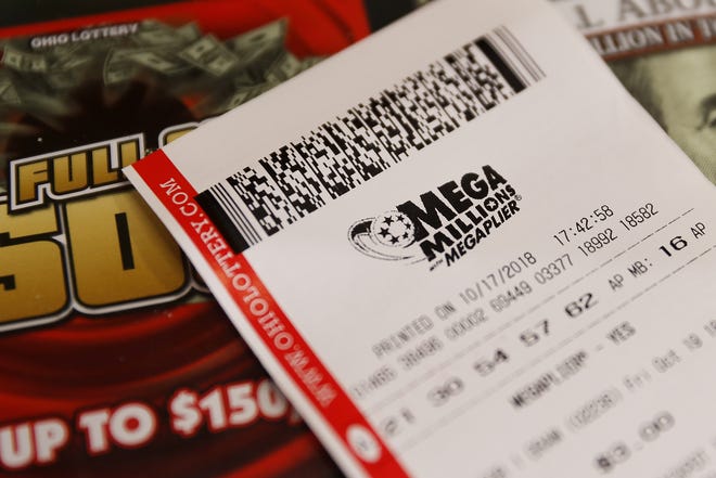 A Mega Millions lottery ticket rests on the shop counter at the Street Corner Market Wednesday in Cincinnati. The estimated jackpot for Friday's drawing would be the second-largest lottery prize in U.S. history with a jackpot estimated to exceed $900 million. [JOHN MINCHILLO/ASSOCIATED PRESS]