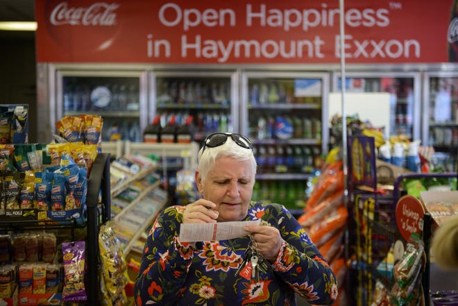 Christel Bungert squints to read the small lettering as she prepares to fill out a lottery ticket at Haymount Exxon on Friday The Mega Millions jackpot has reached $1 billion. "We have our regulars, but this has brought out other people, too," cashier Jade Bacon said of the busy week. "It's been nonstop this week." [Melissa Sue Gerrits/The Fayetteville Observer]