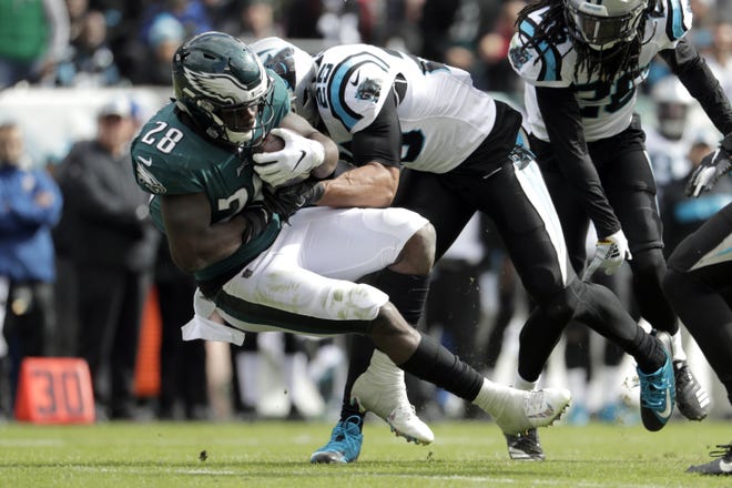 Eagles running back Wendell Smallwood is tackled by Panthers strong safety Eric Reid on Sunday. [MICHAEL PEREZ/ASSOCIATED PRESS]