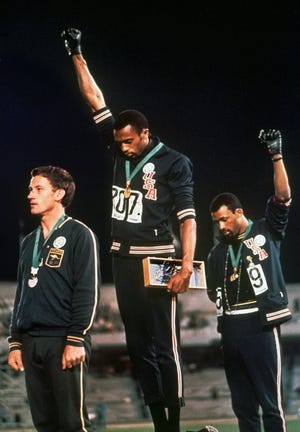 U.S. Olympic sprinters Tommie Smith, center, and John Carlos raise their gloved fists during the playing of "The Star-Spangled Banner" after Smith received the gold medal and Carlos the bronze in the 200-meter dash in Mexico City in October 1968. Australia's Peter Norman, the silver medalist, is at left. [THE ASSOCIATED PRESS FILE PHOTO]