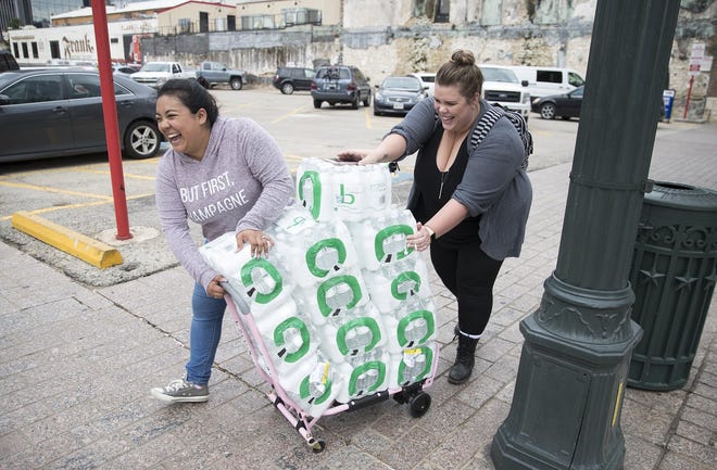 Alyssa Alcala and Katie Killbourne walked at least four blocks from their downtown Austin office after purchasing 12 cases of water from CVS Pharmacy on Congress Avenue. Austin's water utility told all residents early Monday to boil tap water before drinking it. [RICARDO B. BRAZZIELL/AMERICAN-STATESMAN]