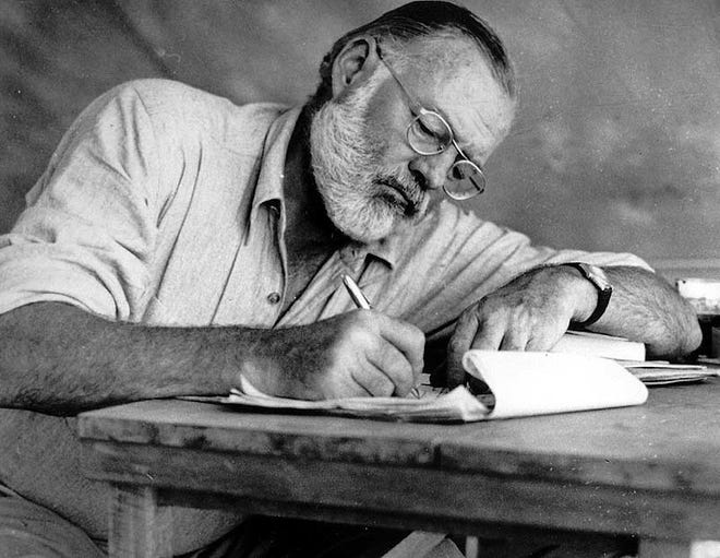 Ernest Hemingway writing while on safari in Africa in 1953 [Photo courtesy of John F. Kennedy Library]