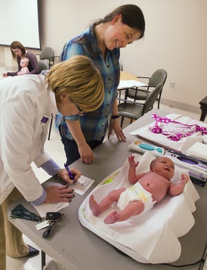 Lactation consultant Lisa Miller records the weight of Amanda Rose's 11-day-old daughter, Violet Devivero, during the Thomasvile and Archdale-Trinity Pediatrics Baby Cafe held at Novant Health Thomasville Medical Center on Thursday night. [Donnie Roberts/The Dispatch]
