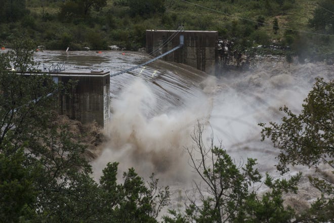 Water from the Colorado River pours over the Max Starcke Dam, Tuesday Oct. 16, 2018, in Marble Falls, Texas. The Llano and Colorado rivers meet at Kingsland and the National Weather Service said both were experiencing "major flooding." A flash flood warning was in effect. (Amanda Voisard/Austin American-Statesman via AP)