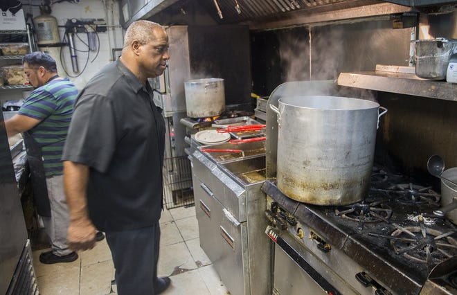 Manager Skip Walker checks out the progress on the boiling water in the kitchen at Hoover's Cooking restaurant on Tuesday. Austin restaurants like Hoover's Cooking were forced to boil water and order extra bottles of water and soda to serve their customers. [RICARDO B. BRAZZIELL/AMERICAN-STATESMAN]