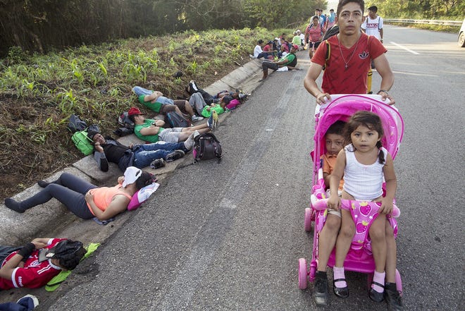 Central American migrant Cristian pushes a carriage occupied by his daughters — Karen, 5, left, and Beiyi, 4, — as they make their way to Mapastepec, Mexico, Wednesday. Thousands of Central American migrants renewed their hoped-for march to the United States on Wednesday, setting out before dawn with plans to travel another 45 miles of the more than 1,000 miles that still lie before them. [RODRIGO ADB/ASSOCIATED PRESS]