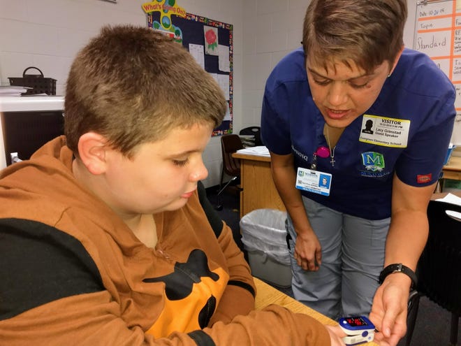 Evergreen Elementary School fourth-grader Devin Pomykaj, 10, learns about oxygen levels from Marion Technical College nursing student Lacy Grimstad on Wednesday during a career day that officials dubbed "DREAMspiration." [Joe Callahan/Ocala Star-Banner]