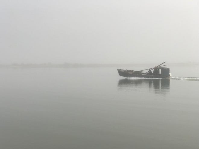 An oyster boat returns to foggy Eastpoint, Fla., after a long day. [Photo by Rick Holmes]