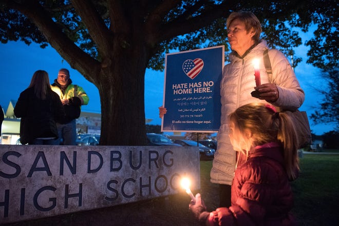 Kathy Westbrook, of Middletown, and her granddaughter, Kelsey Lemp, 3, participate in a candlelight vigil at Sandburg Middle School on Thursday in Middletown. The vigil, which was followed by a meeting, is in response to recent incidents of hateful graffiti at the school. [BILL FRASER / STAFF PHOTOJOURNALIST]