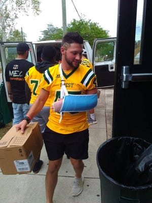 Crest High senior Nate Blantom carries a box of donated items into New Hanover High School in Wilmington. Blanton helped organize a drive to help hurricane victims and helped make the delivery, despite breaking his arm the night before in a football game. [Special to The Star]