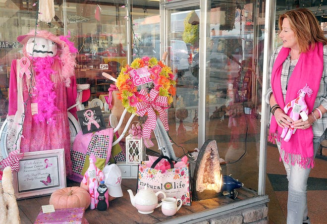 Carla Grimes of Country Bits in downtown Cambridge stands next to the pink window display she created for Breast Cancer Awareness.