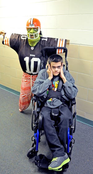 WOOSTER — Student Wesley Puckett of the secondary class poses by a Cleveland Browns player scarecrow who took the top spot in Ida Sue School’s scarecrow contest featuring a number of entries submitted by students and staff. A group of stuffed and decorated paper scarecrows created by the Daily Living class took second place; a traditional scarecrow with a burlap bag head from the primary class, third place; and a Steelers player scarecrow, fourth.