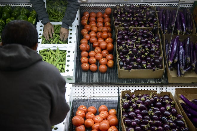 Fresh produce is set on shelving as preparations continue at Around the World Market on Friday. [Melissa Sue Gerrits/The Fayetteville Observer]