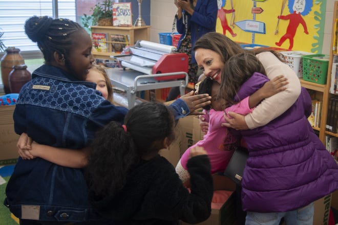 Mary Winfree of the Kiwanis Robeson-Lumberton club on Friday hugs children at W.H. Knuckles Elementary in Lumberton after the club brought hurricane relief supplies to the school for their families. [Paul Woolverton/The Fayetteville Observer]