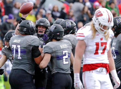 Northwestern quarterback Clayton Thorson (18) celebrates with teammates after scoring a touchdown as Wisconsin linebacker Andrew Van Ginkel (17) looks down at the ground during the first half of an NCAA college football game in Evanston, Ill., Saturday, Oct. 27, 2018. (AP Photo/Nam Y. Huh)