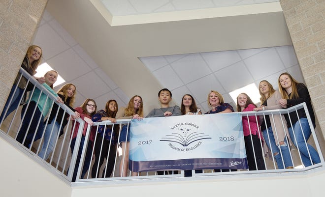Oak Grove High School yearbook advisor Adrianne Quigley (fourth from right) and the school yearbook staff stand by a banner in the school that recognizes their award. [Donnie Roberts/The Dispatch]