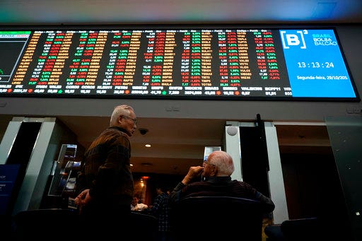Two men talk underneath a display of Brazil's Bovespa index at Sao Paulo's Stock Exchange, Monday, Oct. 29, 2018. The Bovespa index rose in morning trading after far-right politician Jair Bolsonaro was elected president, but it later turned lower and fell 2,24 percent. Stocks climbed earlier this month after Bolsonaro led the previous round of voting, as investors preferred him to leftist parties. (AP Photo/Victor R. Caivano)