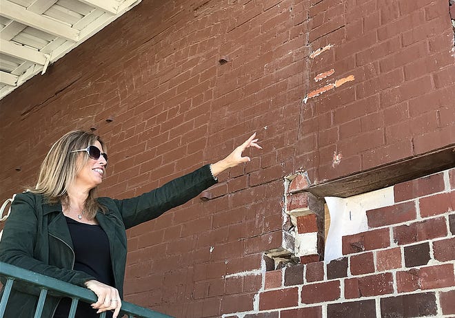 Denise Bradburn, executive director of Discovery Depot ChildrenþÄôs Museum, shows the only remaining portion of the museumþÄôs brick wall that needs to be replaced with new bricks. The museumþÄôs interior and exterior work is near completion, and the new exhibits are slated to open within the first two weeks of February. [REBECCA SUSMARSKI/The Register-Mail]