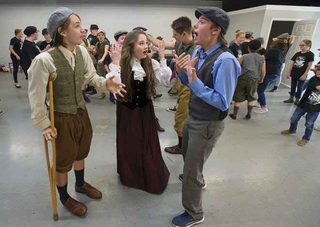 Characters Crutchie, Katherine Plummer and Jack Kelly (from left), played by Isaiah Remole, Frances Gray Riggs and Samuel Stowe, respectively, have a heated discussion while a fight takes place around them in a rehearsal scene from the Lexington Youth Theatre's production of 'Newsies.' [Donnie Roberts/The Dispatch]