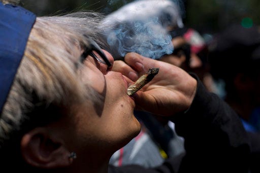 FILE - In this April 20, 2018 file photo, a young man smokes marijuana to celebrate the International Day for Cannabis in Mexico City. Mexico’s Supreme Court issued two more rulings Wednesday, Oct. 31, ordering that complainants in individual cases be allowed to use marijuana for recreational purposes, establishing a precedent which will apply for others that a blanket prohibition is unconstitutional. (AP Photo/Eduardo Verdugo, File)