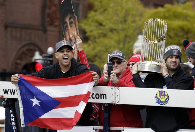 Boston Red Sox manager Alex Cora, left, waves the flag of Puerto Rico as coach Ramon Vazquez holds the championship trophy during a parade to celebrate the team's World Series championship over the Los Angeles Dodgers, Wednesday, Oct. 31, 2018, in Boston. (AP Photo/Elise Amendola)