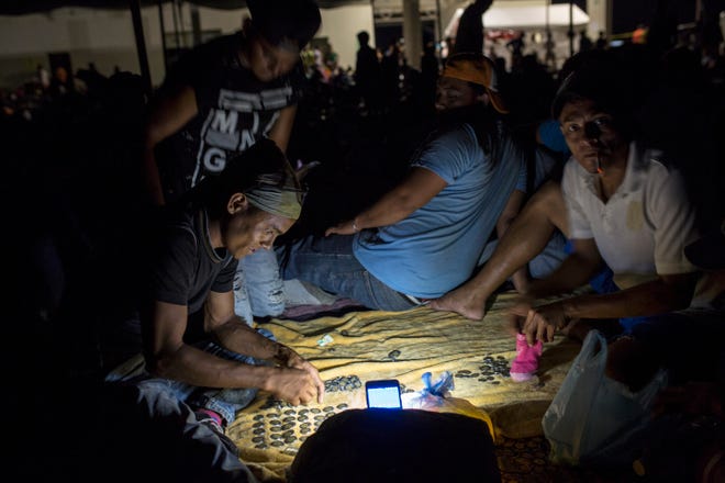 Honduran migrant Nelson Ruiz Madariaga counts coins collected while begging in the street, at a camp set up by a caravan of thousands of Central American migrants in Juchitan, Mexico, Tuesday, Oct. 30, 2018. This caravan of about 4,000 mainly Honduran migrants set up camp Tuesday in the Oaxaca state city of Juchitan, which was devastated by an earthquake in September 2017. A second, smaller migrant caravan is trailing this one in southern Mexico. (AP Photo/Rodrigo Abd)