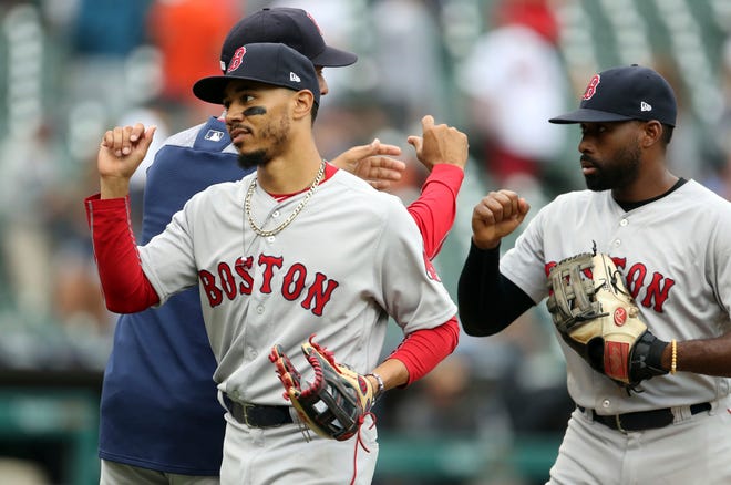 Boston Red Sox right fielder Mookie Betts, front left, and center fielder Jackie Bradley Jr., right, greet teammates after a win over the Detroit Tigers in a baseball game, Sunday, July 22, 2018, in Detroit. (AP Photo/Carlos Osorio)