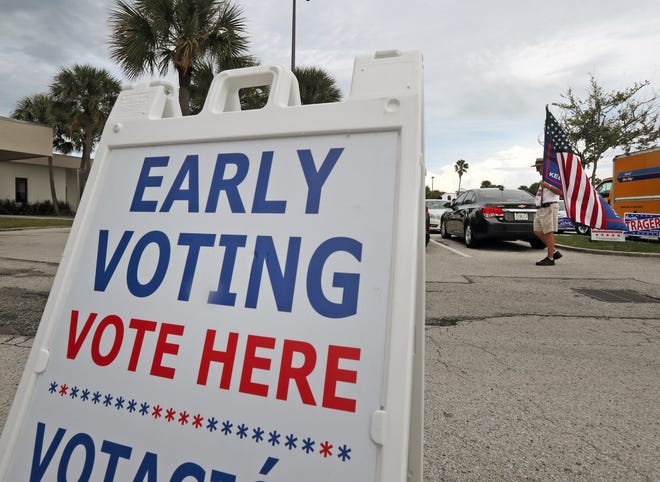 Early voting came to a close in Volusia County on Sunday and in Flagler County on Saturday. A man holds a flag Sunday as he walks outside a voting location in Dayonta Beach. [News-Journal/Nigel Cook]