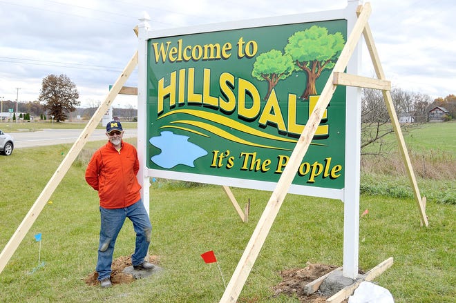 Hillsdale resident Ted Jansen stands beside a new welcome to Hillsdale sign, which brings back the phrase “It’s the People.” Jansen collected donations to install the sign in the lawn at Frank Beck Chevrolet. [SAM FRY PHOTO]