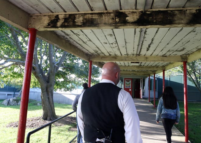 Rogers High School Principal Jared Vance leads a tour through the Newport school last month, walking down an outdoor walkway that has mold along the ceiling. [The Providence Journal / Bob Breidenbach]
