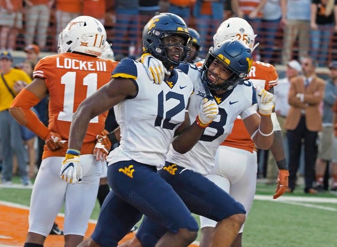 West Virginia receiver Gary Jennings (12) and Marcus Simms celebrate Jenning's touchdown catch during the second half of Saturday's game against Texas. West Virginia won, 42-41.