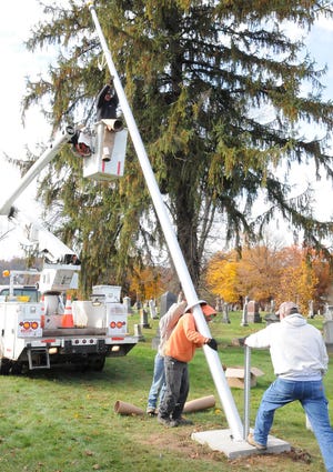 Northwood Cemetery workers hoist one of the three new flagpoles into place Wednesday morning in Old Cambridge Cemetery. The two other poles are located in Northwood Cemetery. They were paid for by the Guernsey County Veterans Commission. Helping was James Green, Skip Wetherell, Tom Bischard, Randy Hossler and Hershell Waugh Jr.
