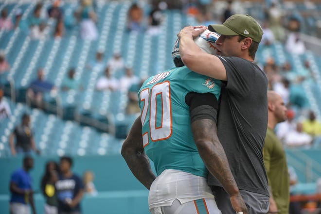 Miami Dolphins head coach Adam Gase embraces safety Reshad Jones during warmups, before the Jets game. [ANDRES LEIVA/Special to the Palm Beach Post]